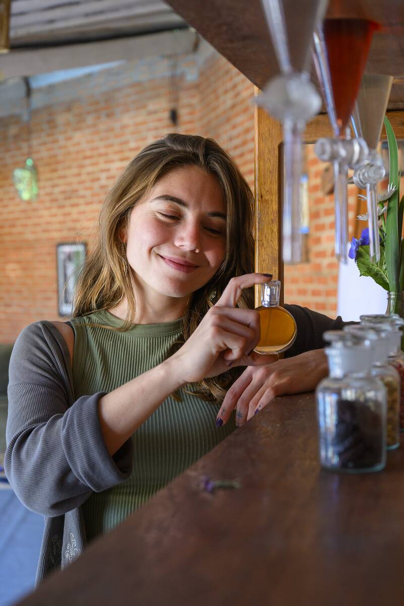 Participante sente o aroma de um frasco âmbar, sorrindo de olhos semicerrados
